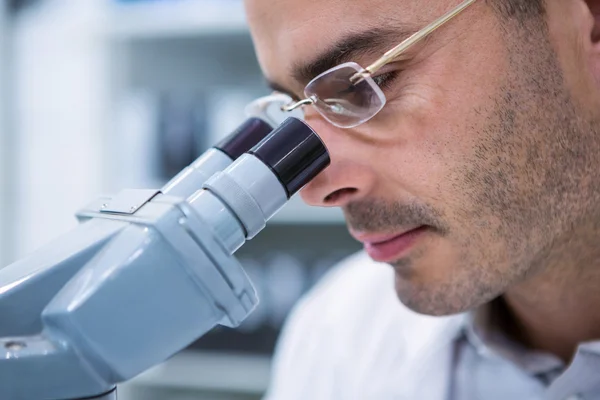 Male optometrist looking through microscope — Stock Photo, Image