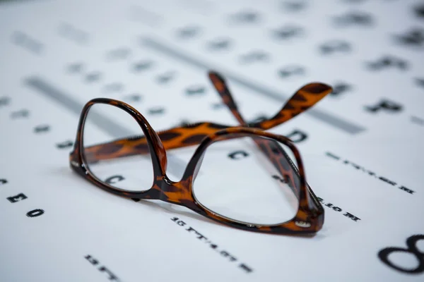 Close-up of spectacles on eye chart — Stock Photo, Image