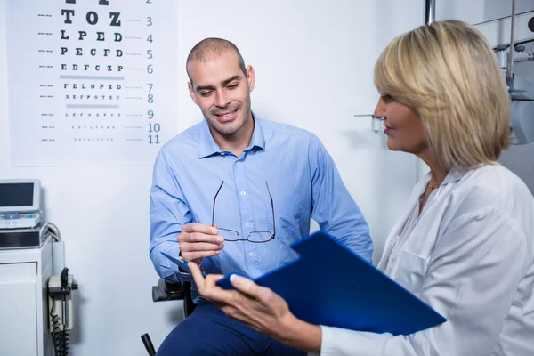 Optometrista femenina hablando con paciente masculino — Foto de Stock