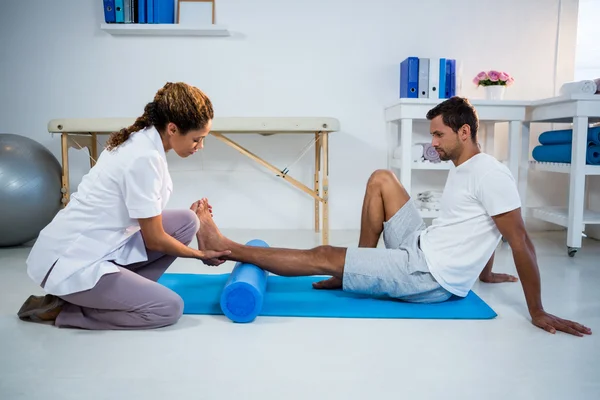 Physiotherapist doing leg therapy to a man — Stock Photo, Image