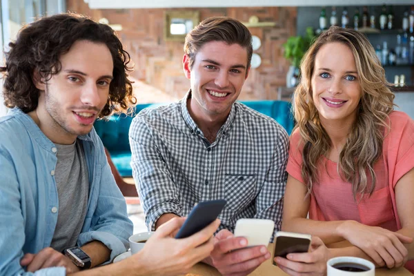 Amigos sonrientes usando su teléfono móvil — Foto de Stock