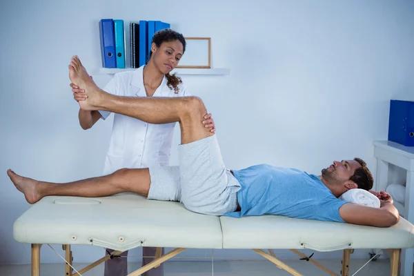 Sjukgymnasten ger ben massage till en patient — Stockfoto