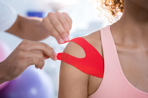 Physiotherapist sticking tape on female patient — Stock Photo, Image