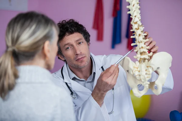 Fisioterapeuta explicando o modelo da coluna vertebral ao paciente — Fotografia de Stock