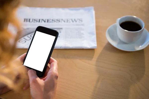 Mujer usando su teléfono móvil con periódico y taza de café en ta — Foto de Stock