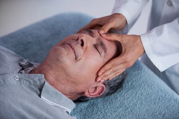 Hombre mayor recibiendo masaje de cabeza de fisioterapeuta — Foto de Stock