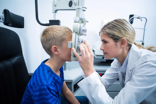 Optometrista femenina examinando paciente joven en foropter — Foto de Stock