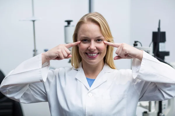 Optometrista feminina apontando para os olhos — Fotografia de Stock