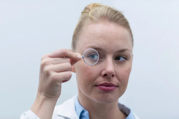 Vrouwelijke optometrist op zoek via Vergrootglas — Stockfoto