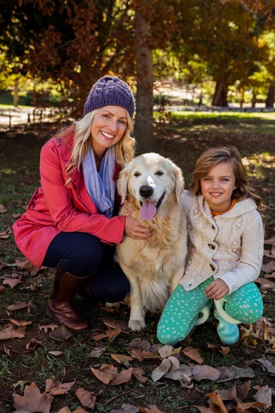 Madre e hija acariciando a su perro — Foto de Stock