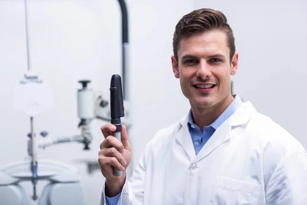 Smiling optometrist holding ophthalmoscope — Stock Photo, Image