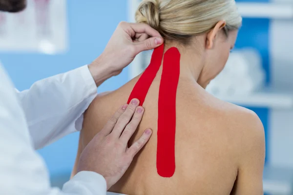 Physiotherapist sticking tape on patient — Stock Photo, Image