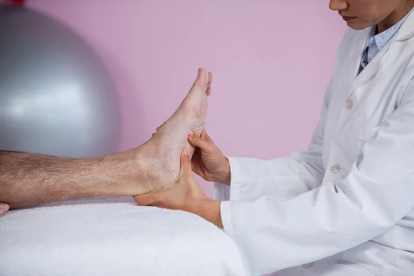 Старший мужчина получает массаж ступней от физиотерапевта — стоковое фото