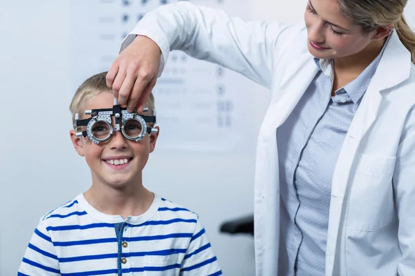 Optometrista femenina examinando paciente joven con foropter — Foto de Stock