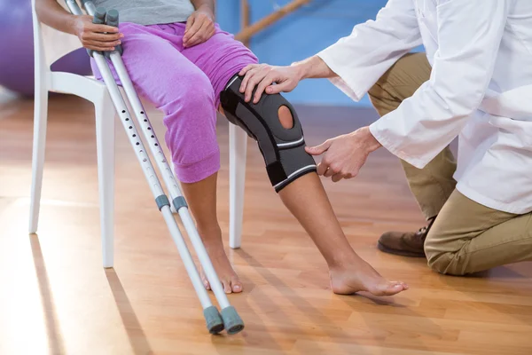 Физиотерапевт, осматривающий женское колено — стоковое фото