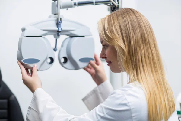 Attentive female optometrist adjusting phoropter — Stock Photo, Image