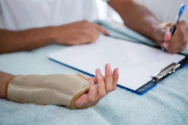 Fisioterapeuta examinando la mano de una paciente femenina — Foto de Stock