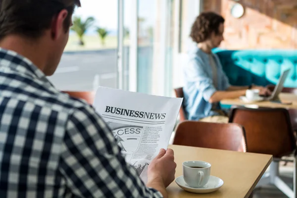 Uomo che legge un giornale aziendale in caffetteria — Foto Stock