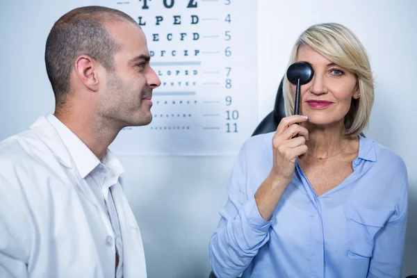 Optometrista examinando paciente femenino con equipo médico — Foto de Stock