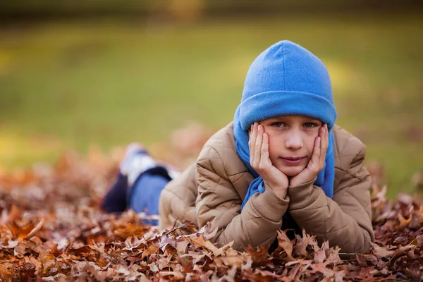 Ragazzo sdraiato al parco durante l'autunno — Foto Stock