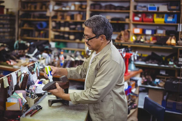 Zapatero aplicando pegamento en el zapato — Foto de Stock