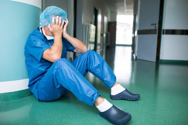 Triste cirujano sentado en el suelo en el pasillo — Foto de Stock