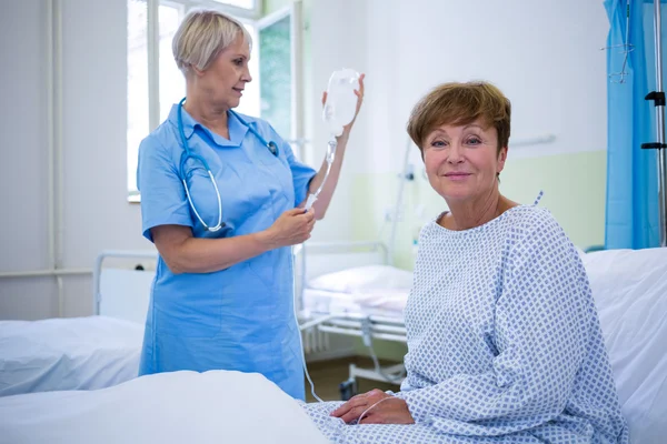 Glimlachend patiënt zittend op bed — Stockfoto