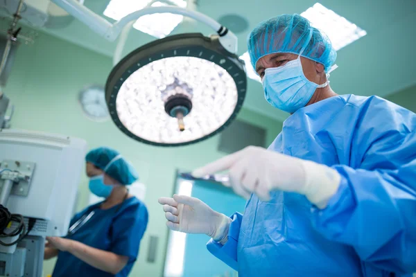 Хирург держит хирургический инструмент в операционной — стоковое фото