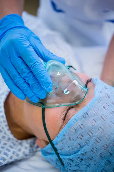Медсестра надевает кислородную маску на лицо пациента — стоковое фото