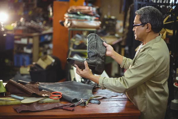 Schuhmacher untersucht einen Lederstiefel — Stockfoto