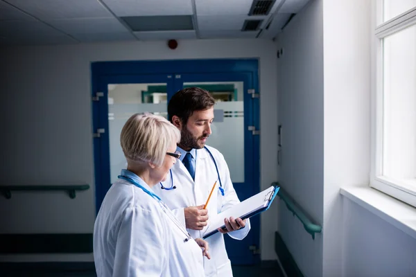 Doctors discussing over clipboard — Stock Photo, Image