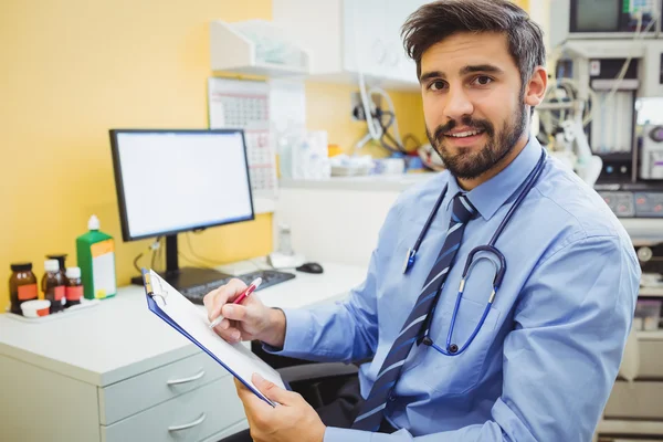Doctor writing on a clipboard — Stock Photo, Image