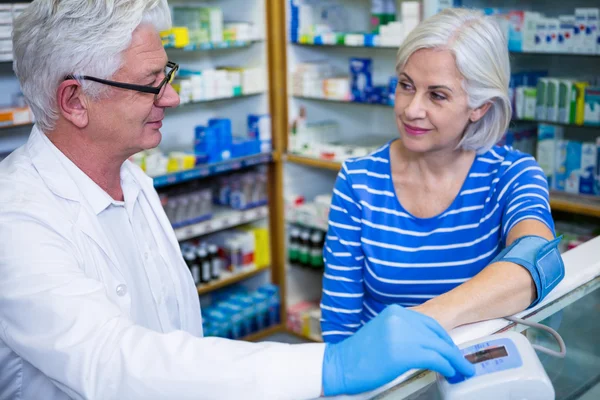 Farmacêutico verificando a pressão arterial do cliente — Fotografia de Stock