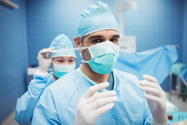 Nurse helping surgeon in tying surgical mask — Stock Photo, Image