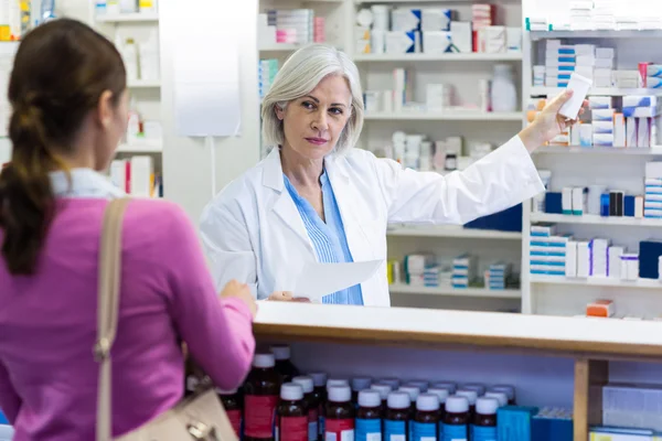 Farmacista che mostra bottiglia di farmaco al cliente — Foto Stock