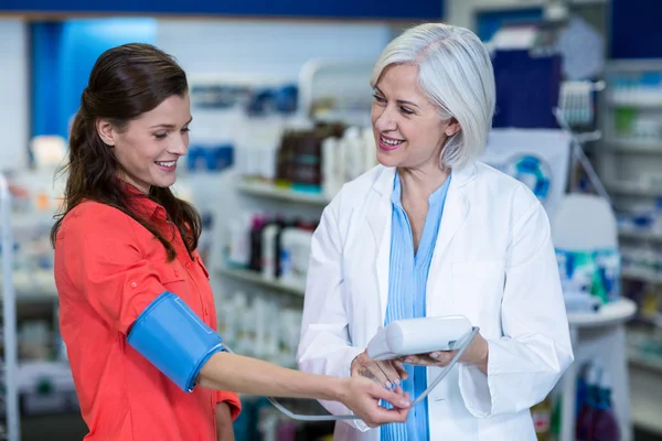 Farmacêutico verificando a pressão arterial do cliente — Fotografia de Stock