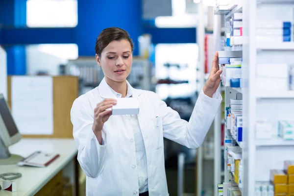 Pharmacist checking medicine in shelf — Stock Photo, Image