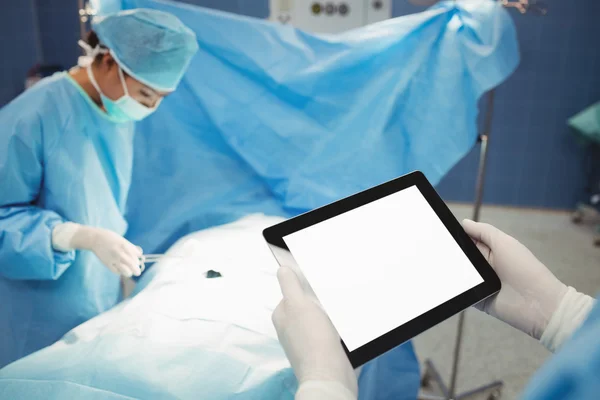 Surgeon using digital while nurse operating patient — Stock Photo, Image