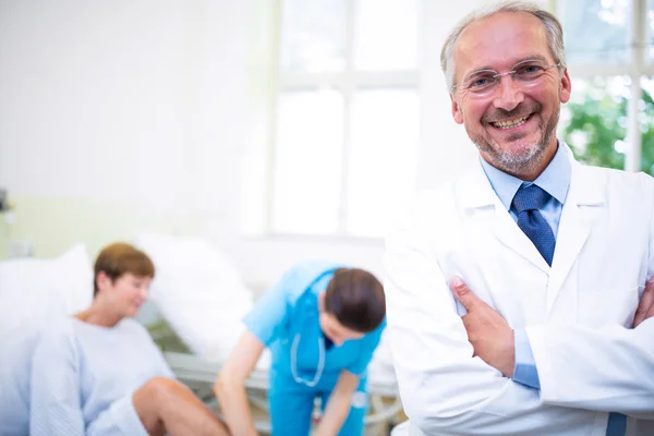 Médico sorridente de pé com os braços cruzados — Fotografia de Stock