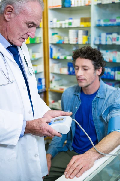 Farmacéutico control de la presión arterial del cliente — Foto de Stock