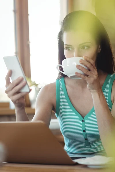 Mujer usando el teléfono mientras toma café — Foto de Stock