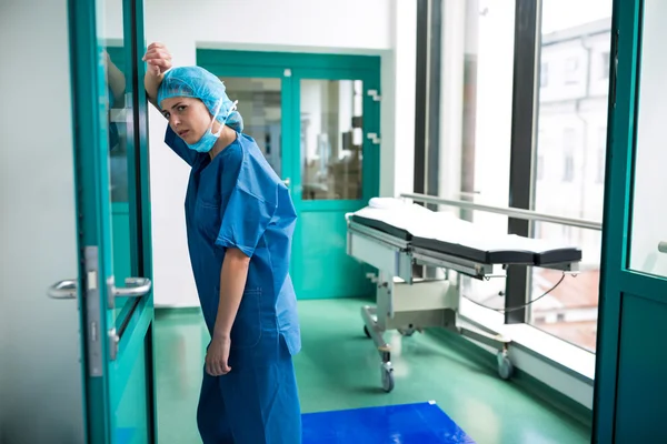 Trauriger Chirurg lehnt an Glastür — Stockfoto