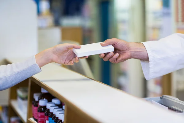 Pharmacist giving a box of medicine to customer — Stock Photo, Image