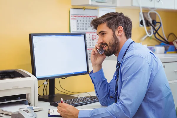 Lekarz siedzi przy biurku i rozmowy na telefon — Zdjęcie stockowe