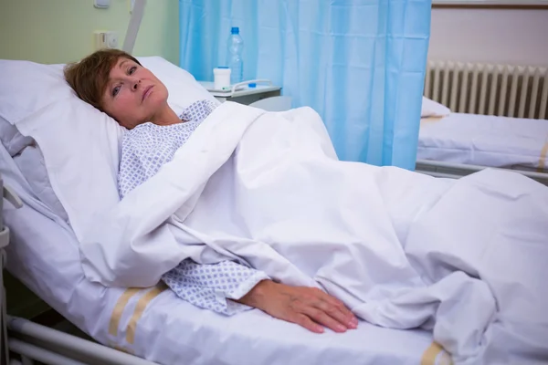 Sad senior patient lying on a bed — Stock Photo, Image