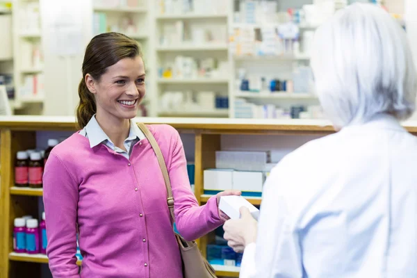 Pharmacist giving medicine box to customer — Stock Photo, Image