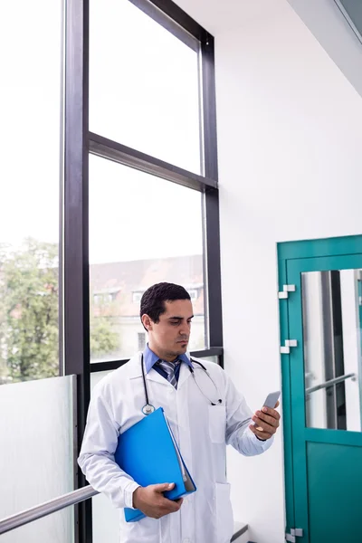 Doctor using phone in corridor — Stock Photo, Image