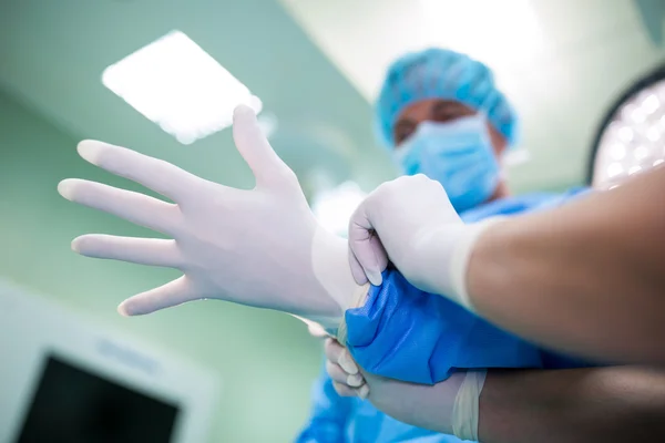 Nurse helping surgeon in wearing surgical gloves — Stock Photo, Image