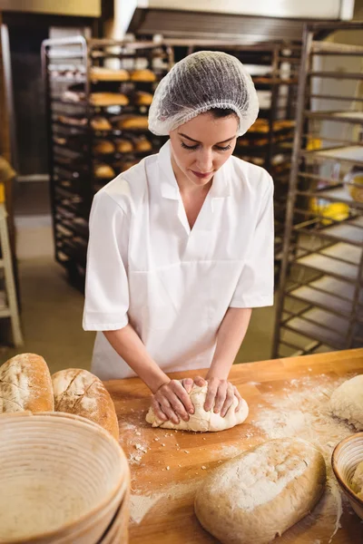 Vrouwelijke bakker kneedt een deeg — Stockfoto