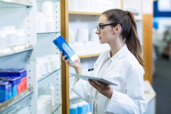 Pharmacist holding tablet while checking medicine — Stock Photo, Image